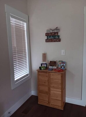 A room with a window, a wooden cabinet with various items, and a motivational sign on the wall.