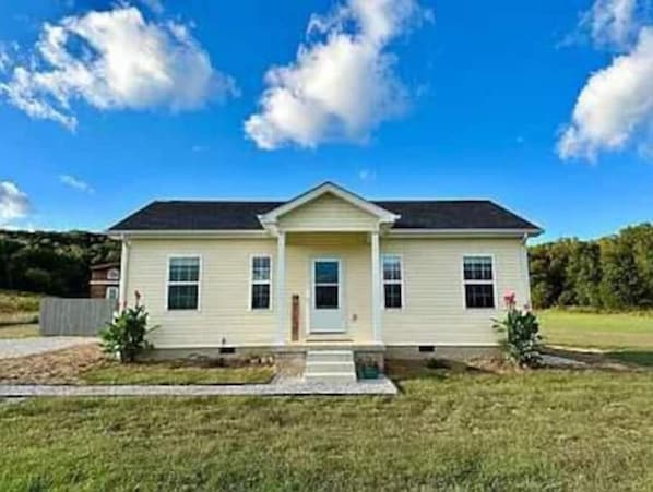 A two-story house with a front porch, a small front yard, and a clear blue sky.