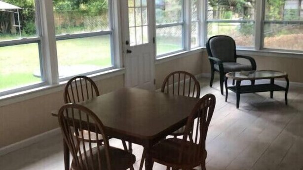 Comedor con una mesa, cuatro sillas, ventanas amplias y vista al jardín trasero.