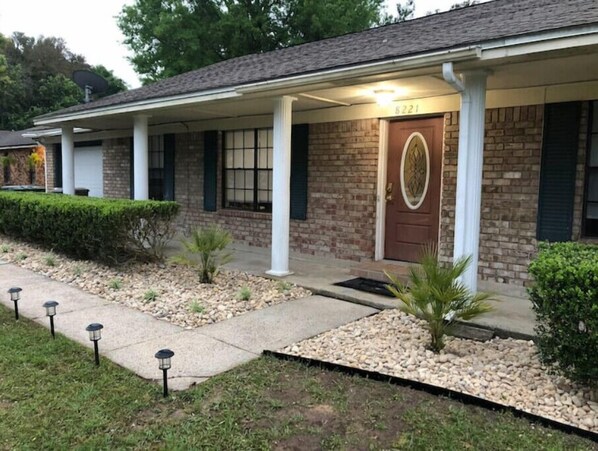 Stunning single-story home with a brick facade, a covered porch, and a beautifully manicured lawn.