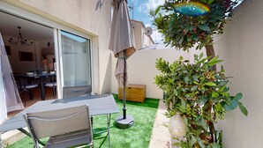 Une terrasse avec une table et des chaises, un parasol et un pot de fleurs.