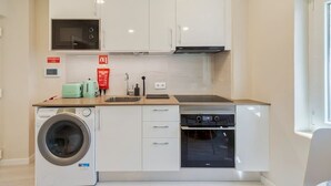 A compact kitchen with a washing machine, microwave, and oven. - Bonneville Setúbal II (Setúbal)