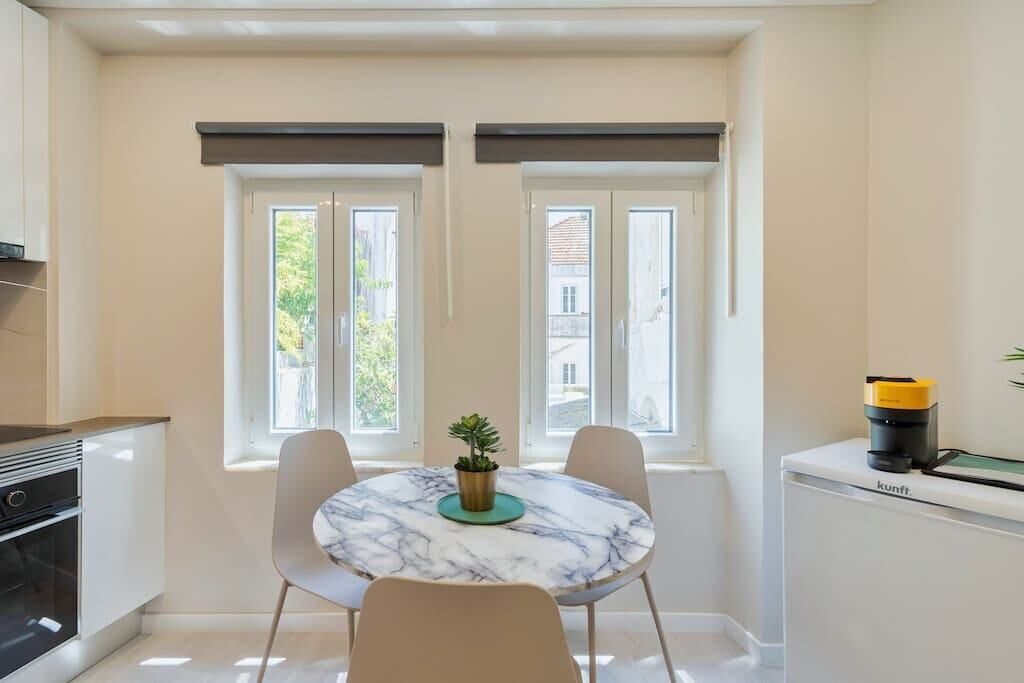 A modern kitchen with a marble table, two chairs, and a small potted plant.