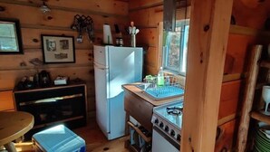 A compact kitchen with a refrigerator, stove, sink, and wooden cabinets.