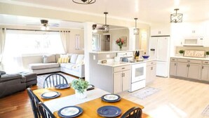 Une cuisine moderne avec des meubles blancs, un îlot central et des luminaires suspendus.