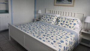 Un dormitorio con cama, mesita de noche, lámpara, un cuadro en la pared y armario.