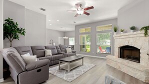 Ein modernes Wohnzimmer mit einem grauen Sofa, einem Couchtisch und einem Kamin.