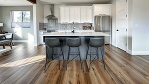 A modern kitchen with a central island, bar stools, stainless steel appliances, and a large window. - Sedona Sky View (Sedona)