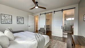 A bedroom with a large bed, a ceiling fan, and a sliding door leading to a bathroom. - Sedona Sky View (Sedona)