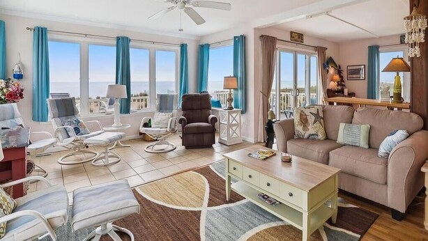A spacious living room with a sofa, armchairs, a coffee table, and a ceiling fan. - Beautiful Oceanfront Beach House for the whole family and more (Bethany Beach)