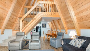 Ein geräumiges Loft mit einer Holztreppe, einem Essbereich und einer gemütlichen Sitzecke mit Ledersofas.