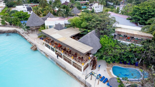 Ein Resort mit Pool, strohgedeckten Gebäuden und Blick auf den Strand.