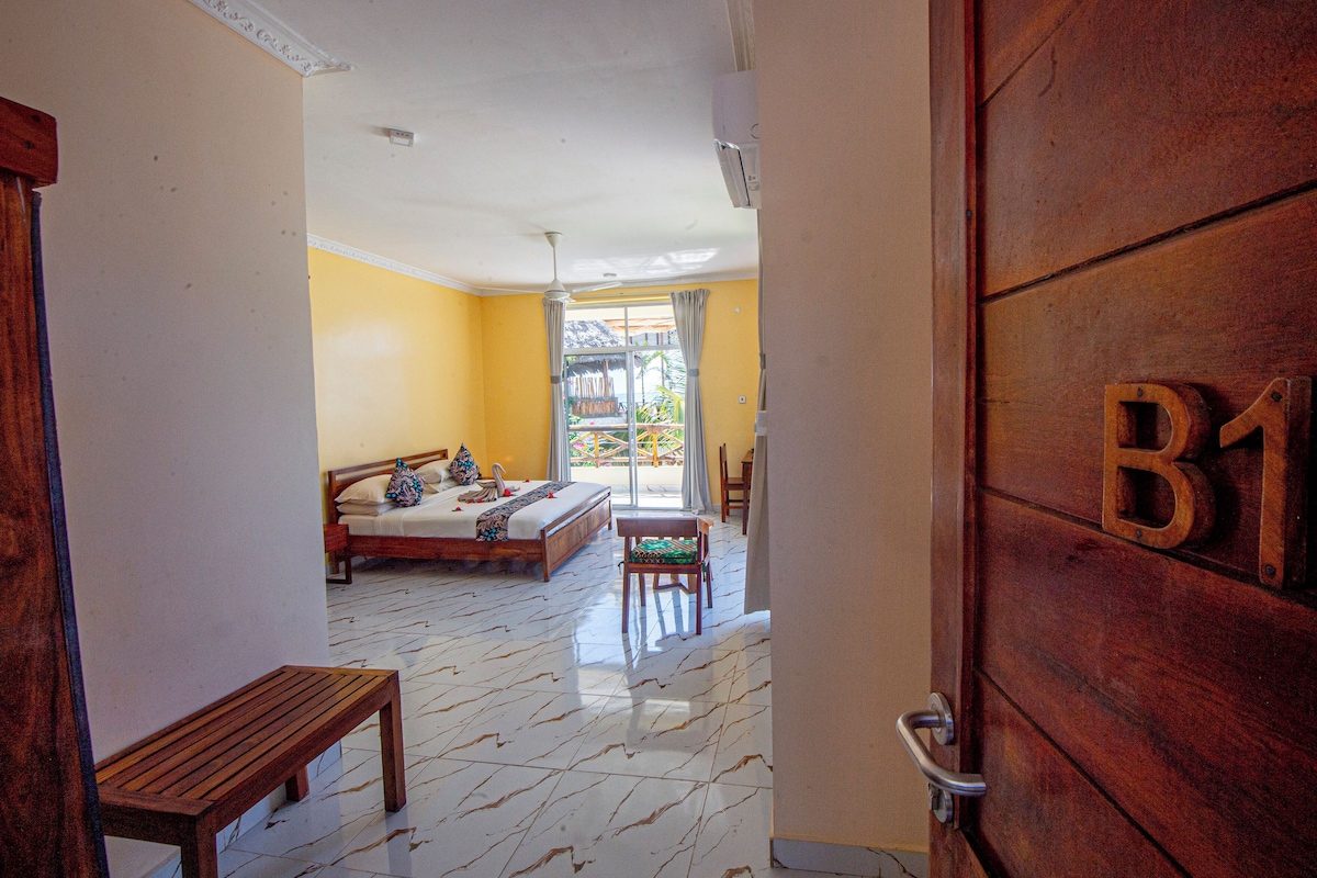 Een hotelkamer met een bed, een bankje en een houten deur met het nummer 11.