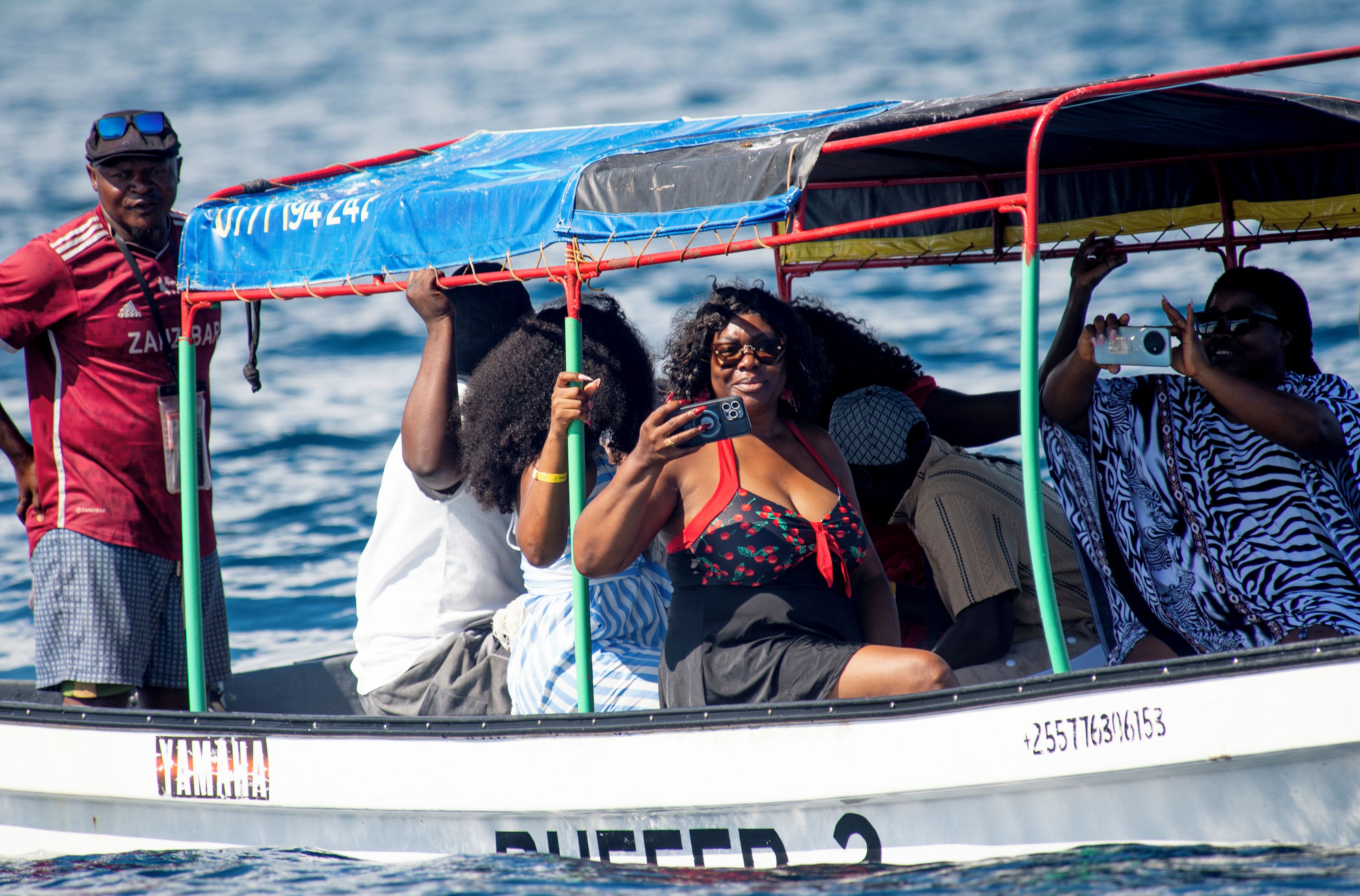 A boat with a blue tarp and a person taking a photo.