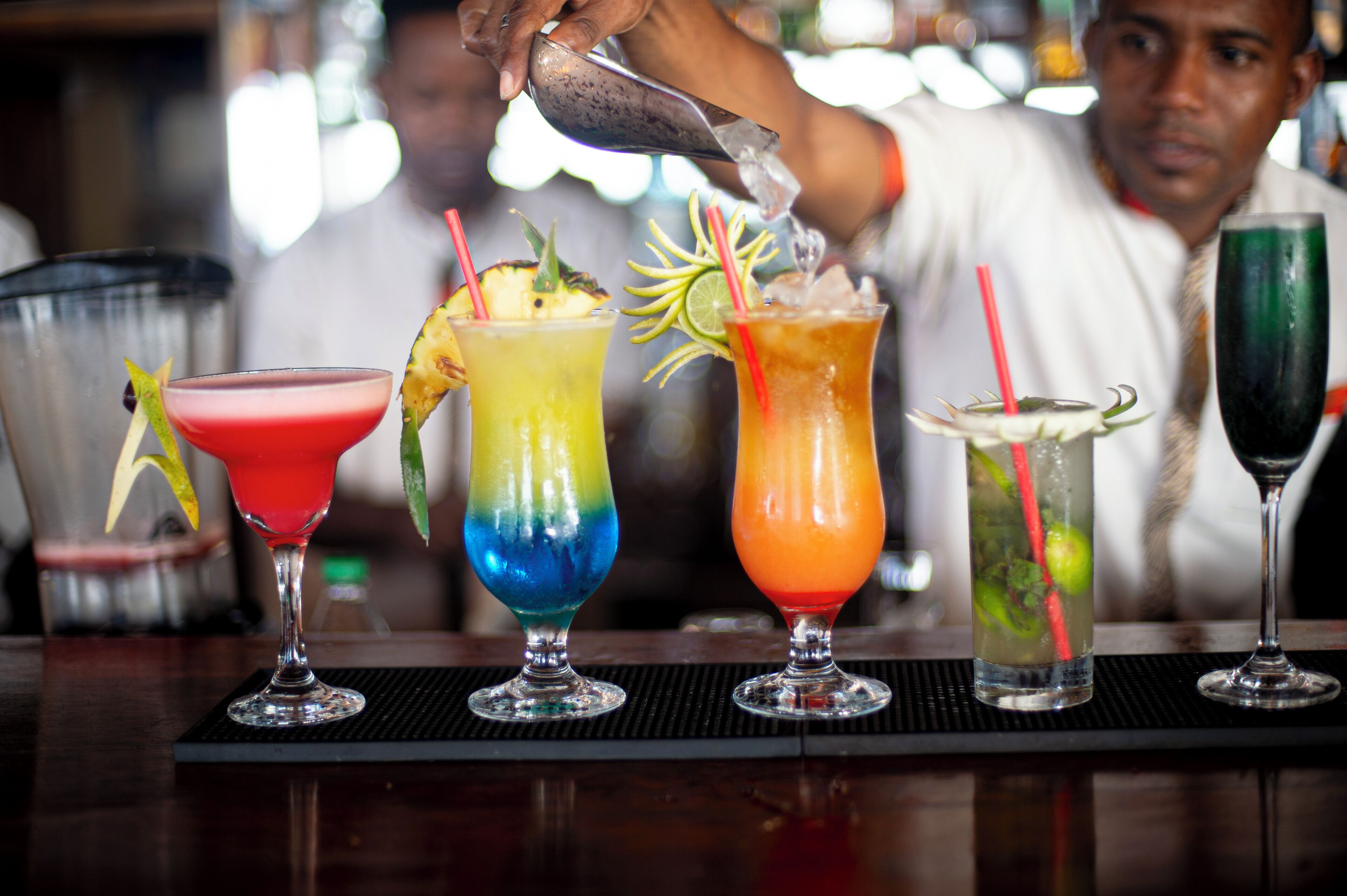 Un barman prépare des cocktails colorés, en y ajoutant des pailles et des décorations.