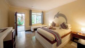 Ein Hotelzimmer mit Bett, Schreibtisch, Sitzbank, Fenster und einem Wandgemälde mit Delphinen.