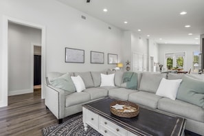 A modern living room with a sectional sofa, a coffee table, and framed artwork on the wall. - *Sea Salt by the sand* Walk to beach/seafood/fishing (Gulfport)