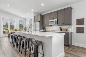 A modern kitchen with a large island, bar stools, and dark cabinets. - *Sea Salt by the sand* Walk to beach/seafood/fishing (Gulfport)