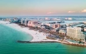 An aerial view of a coastal resort with beachfront properties, a marina, and a large hotel complex.