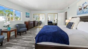 Habitación de hotel con cama, escritorio, silla, cómoda y vista al exterior.