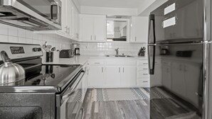 Una cocina moderna con gabinetes blancos, electrodomésticos de acero inoxidable y una alfombra estampada.