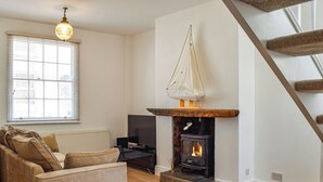A cozy living room with a fireplace, a sofa, a TV, and a staircase. - 2 bedroom accommodation in Crosby, near Liverpool (Crosby, near Liverpool)