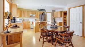 A spacious kitchen with wooden cabinets, a central island, and a round dining table with chairs. - Montana Vacation Rental: 32 Mi to Yellowstone! (Emigrant)