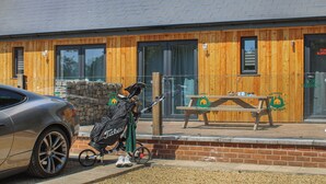 Un bâtiment avec une façade en bois, un banc et une poussette.