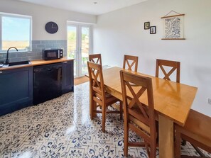 Una cocina con una mesa de comedor y sillas, un reloj y una ventana.