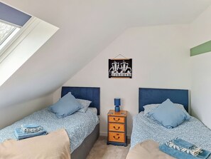 A bedroom with two beds, a dresser, a wall clock, and a framed picture.