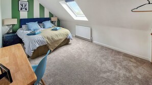 Een slaapkamer met een bed, een bureau, een stoel, een radiator en een dakraam.
