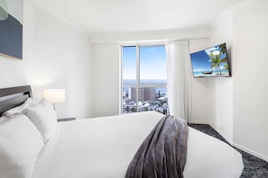 A hotel room with a large bed, a TV on the wall, and a window with a city view. - Chevron Renaissance Ocean View (Surfers Paradise)