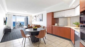 A modern kitchen with a dining area, large windows, and a view of the city.