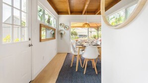 Un espace repas doté d’un plafond en bois, de murs blancs et d’une grande fenêtre.