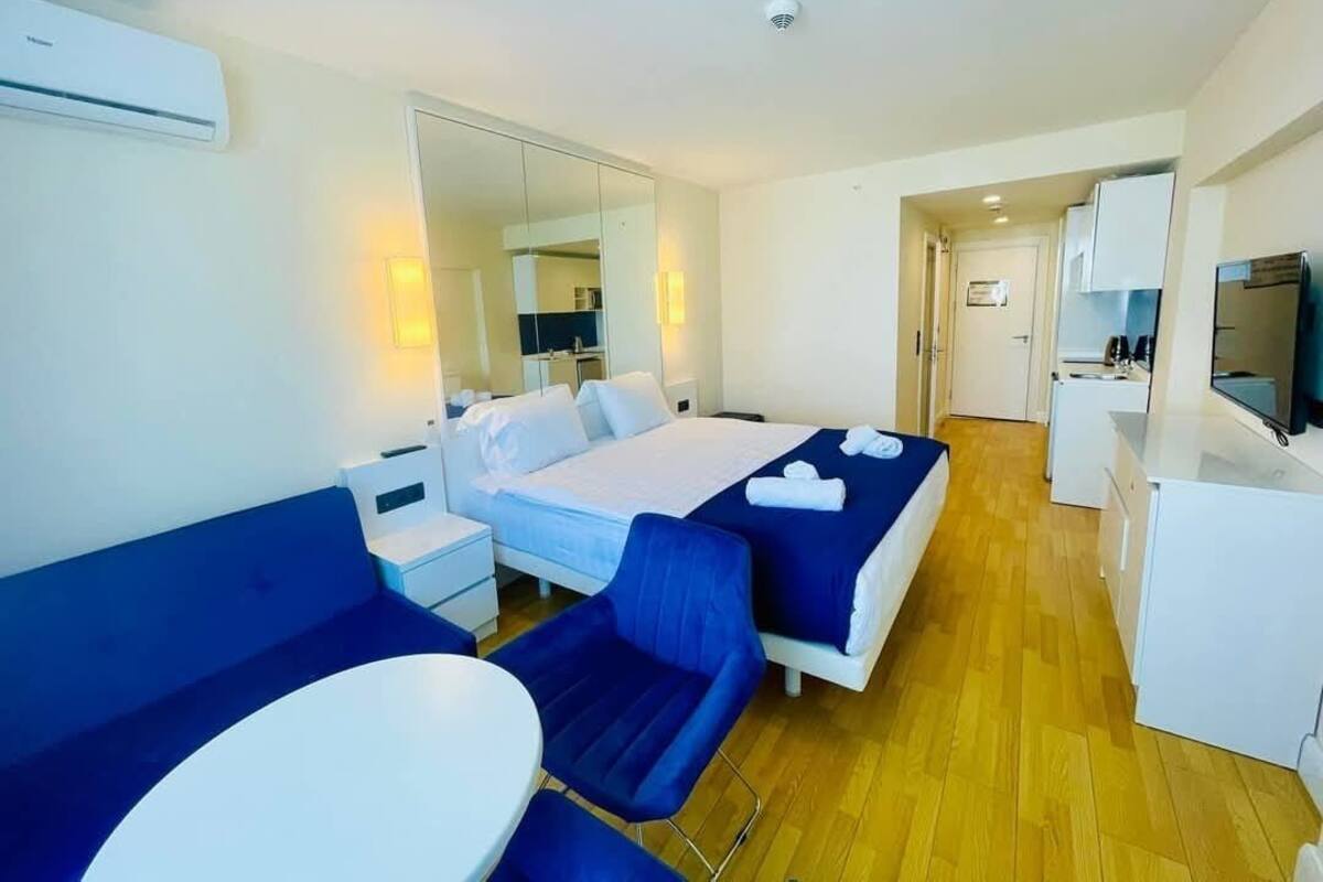 Une chambre d’hôtel comprenant un lit, un bureau, une chaise, une petite table et un miroir.