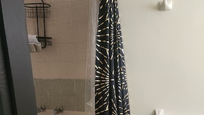 Ein Badezimmer mit Dusche, einem Handtuchhalter mit weißem Handtuch und einem Duschvorhang mit goldenem Muster.