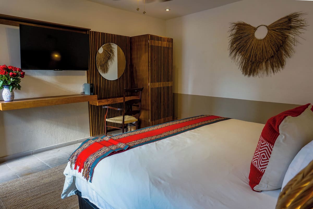 Ein Schlafzimmer mit einem Bett, einem an der Wand montierten Fernseher, einem Holztisch und einem Stuhl.