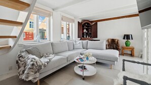 A modern living room with a grey sectional sofa, a white coffee table, and a wooden cabinet. - 1 bedroom cozy home in Svaneke (Svaneke)