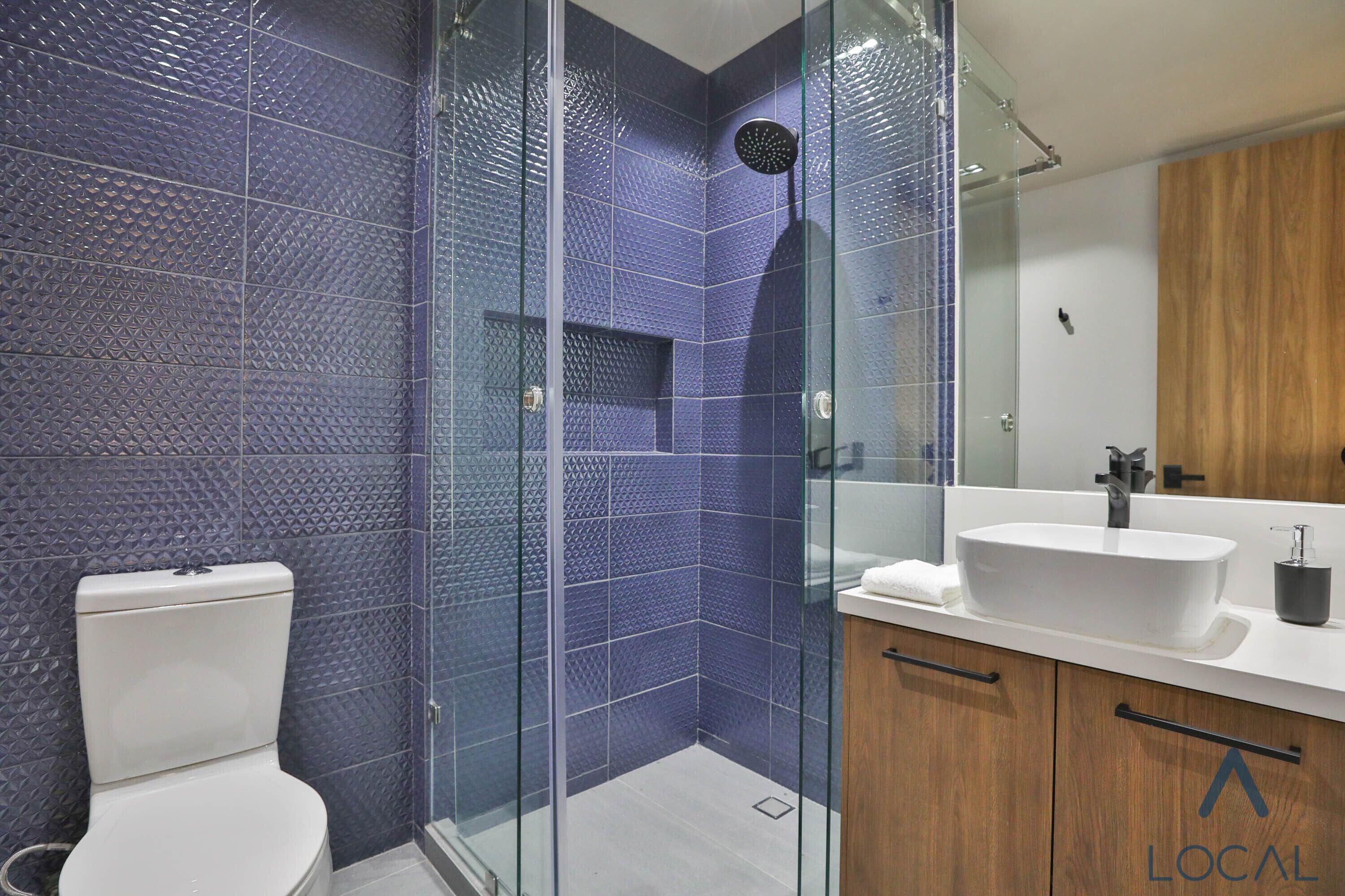 Une salle de bain moderne avec une douche à parois de verre, des toilettes blanches et un meuble-lavabo en bois avec un évier.