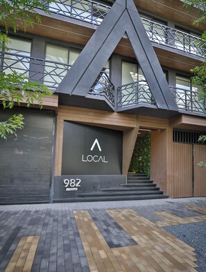 Un edificio moderno con un llamativo letrero que dice 'LOCAL', con un diseño geométrico y una escalera que lleva a la entrada.