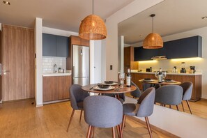 Una cocina moderna con armarios de madera, un comedor con sillas grises y una mesa redonda para dos.