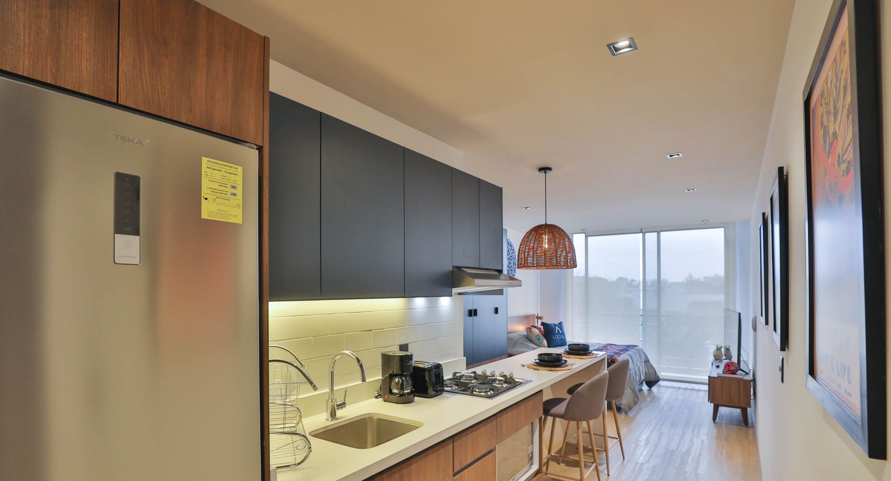 Eine moderne Küche mit einem Edelstahl-Kühlschrank, einem Einbauofen und einem großen Fenster mit Blick auf eine Skyline.