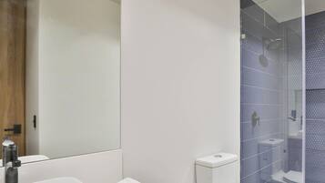 A modern bathroom with a white sink, a toilet, and a glass-enclosed shower area.