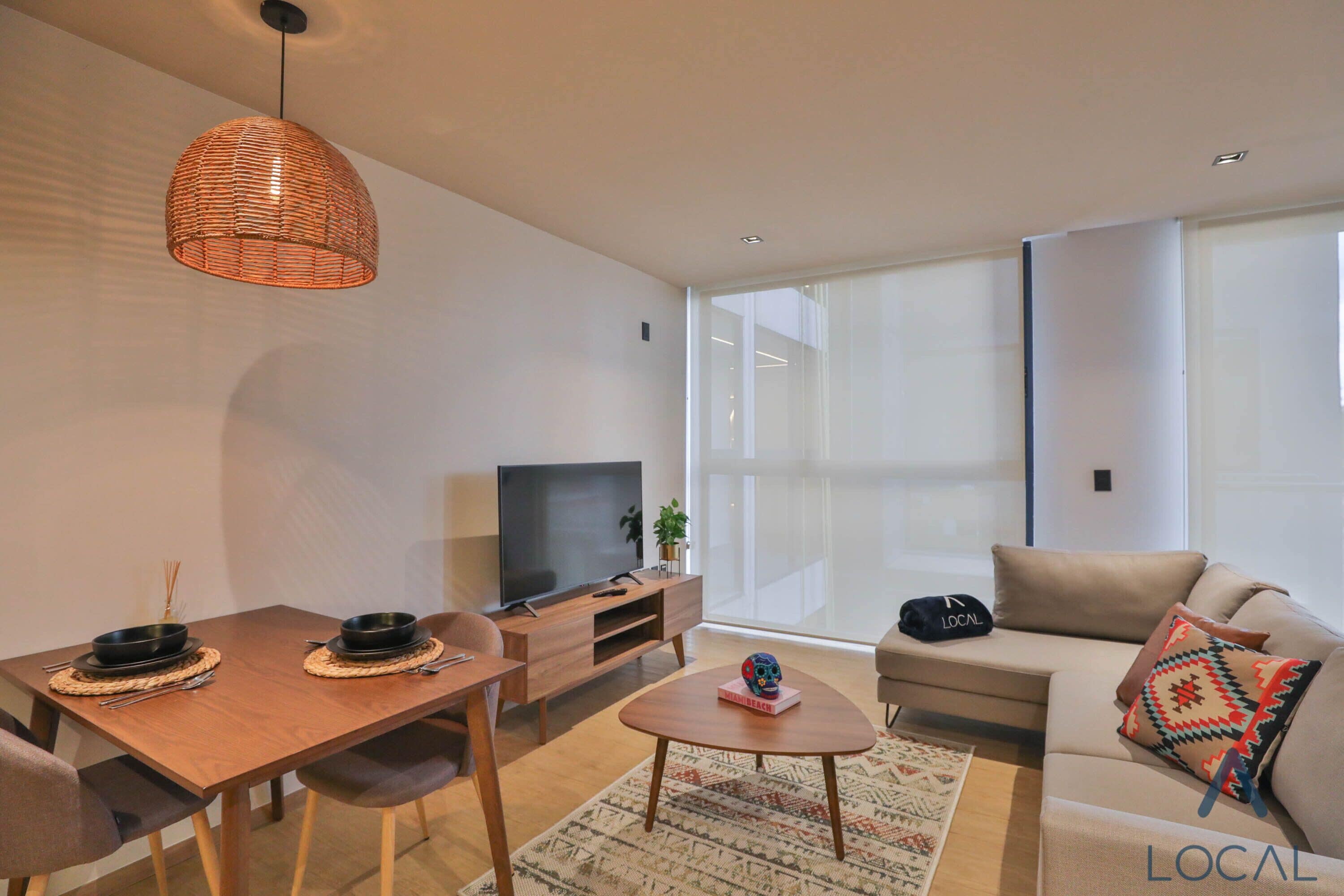 Un salon moderne avec une table à manger en bois, un canapé et un téléviseur.