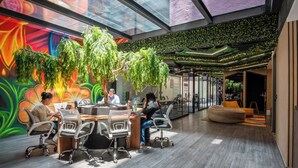 A modern office space with a glass ceiling, green wall plants, and a colorful mural. - Be Local Lofts & Coworking (Mexico City)