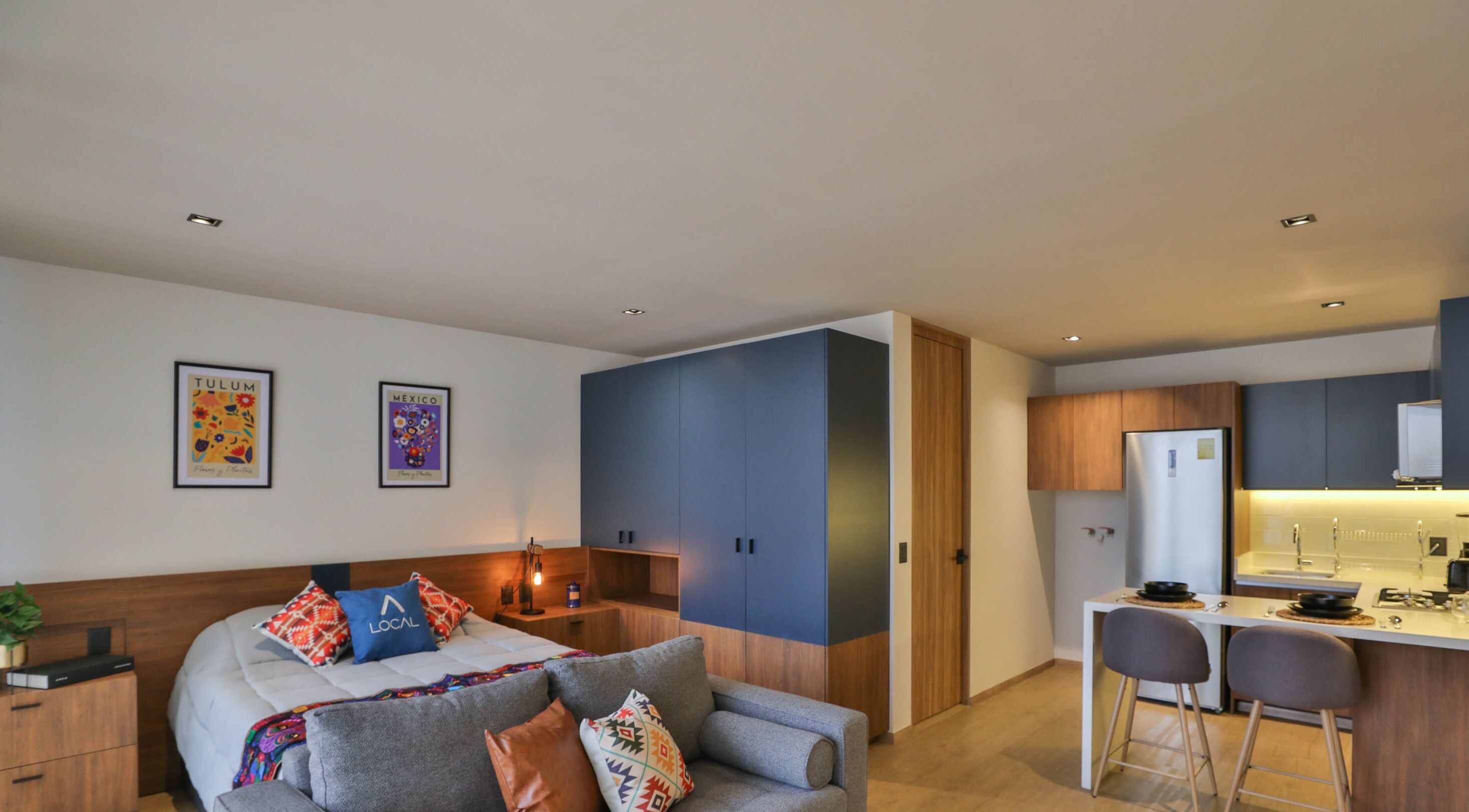 Ein modernes Hotelzimmer mit Bett, Schreibtisch und einer Küchenzeile.