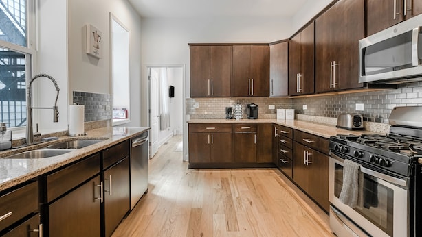 Una cocina moderna con armarios de madera oscura, electrodomésticos de acero inoxidable y salpicadero de azulejos.