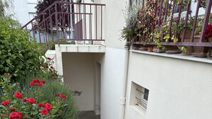 A narrow concrete pathway flanked by a white wall and a metal railing.