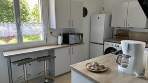 A modern kitchen with white cabinets, a coffee maker, a microwave, and a washing machine.