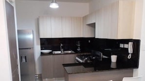 Una cocina moderna con refrigerador, estufa y taburetes blancos.